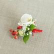 A finely detailed close-up of a hand-crafted boutonniere rests on a softly textured, oat-toned linen fabric, the neutral background echoing the calm, understated elegance of De Beauvoir Town's quiet side streets. At the heart of the design sits a pristine white Phalaenopsis orchid, its wide, velvety petals unfurling like wings, with a gentle wash of creamy yellow and soft orange glowing in the throat. Around the orchid, tiny white clouds of baby's breath float in delicate clusters, each miniature floret catching the light and adding a feathery softness. Lush green leaves in mixed shapes-some broad and pointed, others slender and elongated-frame the central flower and give the arrangement a fresh, garden-picked feel, as if it has just been carried in from a hidden courtyard near De Beauvoir Square. Nestled to one side, a tight cluster of glossy red berries brings a rich, festive accent, their rounded forms gleaming against the calmer whites and greens, while a few pale green berry buds hint at new growth and freshness. The stems are gathered neatly and wrapped with a deep red satin ribbon, tied in a compact, confident knot with short tails that lie smoothly along the fabric, suggesting readiness to be pinned to a lapel for a wedding, prom, or winter celebration. The overall composition feels intimate and intentional, like something chosen with care by a local De Beauvoir Town florist to sit close to the heart during a meaningful moment.
